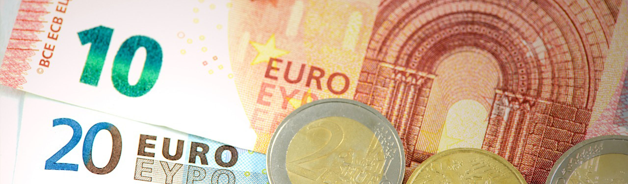 ein Zehneuroschein und ein zwanzigeuroschein mit verschiedenen Euromünzen darauf liegend